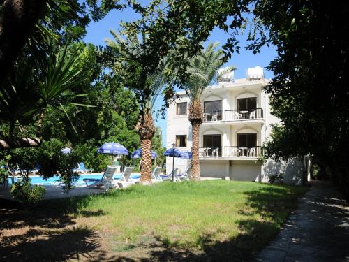 a building with a swimming pool and palm trees at Odysseas & Eleni Hotel Apartments in Polis Chrysochous