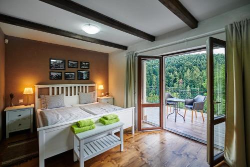 a bedroom with a white bed and a balcony at Sad nad Klingerom in Banská Štiavnica