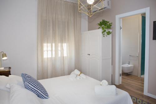 a bedroom with a white bed and a bathroom at AmaSi Affittacamere in Siracusa