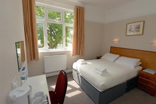 a bedroom with a bed and a desk and a sink at Clarence House Hotel in Tenby