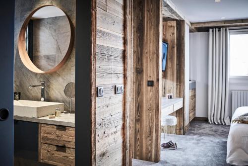 a bathroom with a wooden wall and a mirror at Hotel Altitude in Val-d'Isère