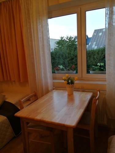 a wooden table in front of a window with flowers on it at Noclegi u Mai in Olsztyn