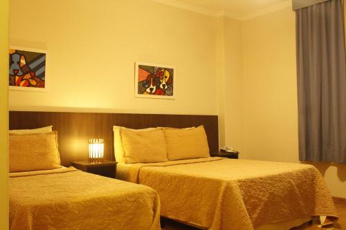 a hotel room with two beds and a window at Hotel Mount Everest in Nova Friburgo