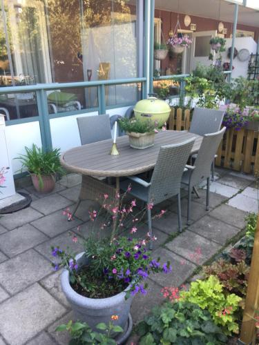 un patio con mesa, sillas y flores en Farsta Bed and Breakfast, en Estocolmo