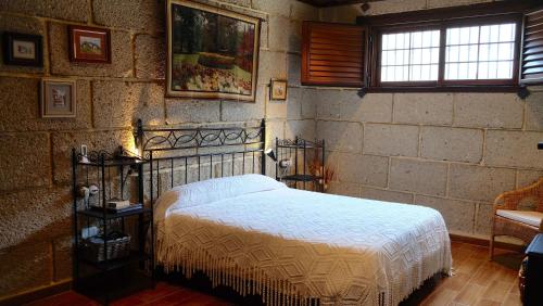 a bedroom with a bed and a brick wall at Casa en finca de uva con piscina privada, cubierta y climatizada in La Degollada
