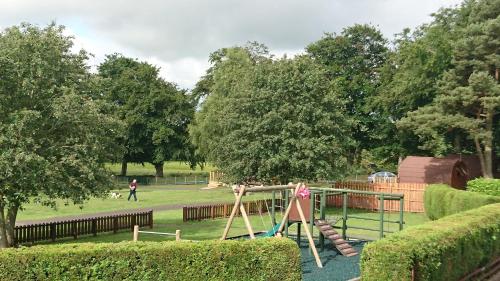 a playground with a slide in a park at Drumshademuir Caravan & Camping Park in Glamis