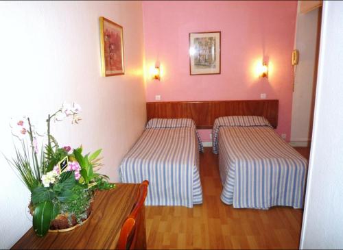 Zimmer mit 2 Betten und einem Tisch mit einer Blumenvase in der Unterkunft Hôtel Du Brabant in Paris