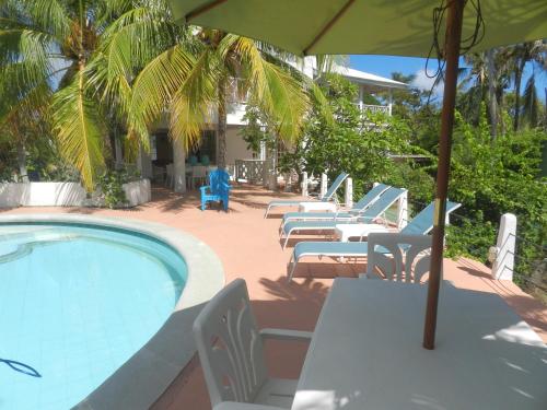 a pool with tables and chairs and an umbrella at Ocean View Sai in San Andrés