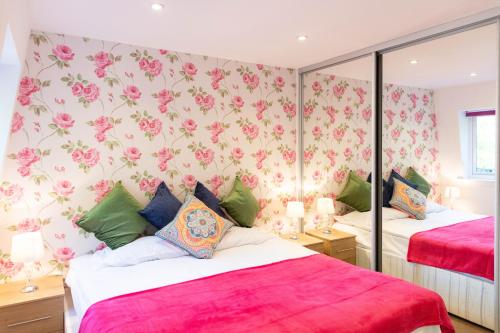 ケンブリッジにあるPenthouse with Terrace 5 mins walk to Colleges & City Centre & Sleeps 6のピンクの花の壁紙を用いたベッドルーム1室(ベッド2台付)