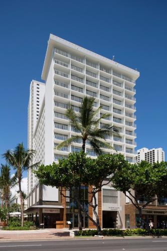a tall white building with a palm tree in front of it at 'Alohilani Resort Waikiki Beach in Honolulu