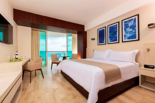 a hotel room with a large bed and a desk at Krystal Grand Cancun All Inclusive in Cancún