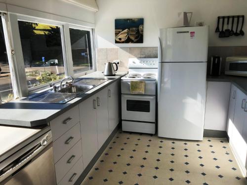 
a kitchen with a refrigerator, stove, sink and dishwasher at Bluewater House in Narooma
