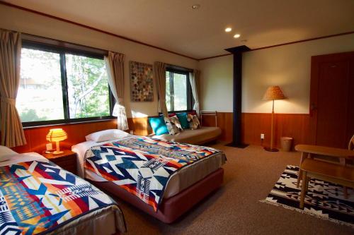 1 dormitorio con 2 camas y sofá en Okushiga Lodge Yama no Manimani, en Yamanouchi