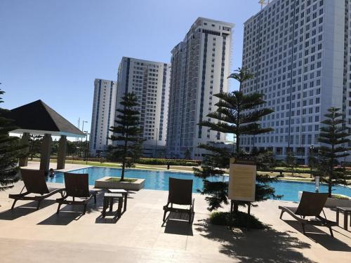 een zwembad met stoelen en een tafel en enkele gebouwen bij Rm Staycation TaalView Smdc in Tagaytay