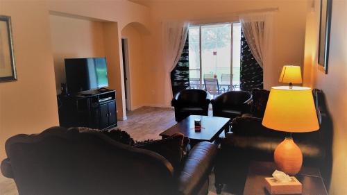 un soggiorno con divano, tavolo e TV di Maya's Villa a Haines City