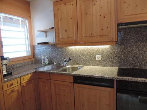 uma cozinha com armários de madeira e um lavatório em Preschaint (720 Kü) em Valbella