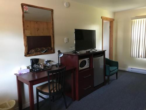 Dieses Hotelzimmer verfügt über einen Schreibtisch mit einem TV und einem Schreibtisch sidx sidx sidx sidx sidx. in der Unterkunft Deep River Motel in Deep River