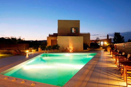 a swimming pool at night with a building in the background at Petradi in Livadi