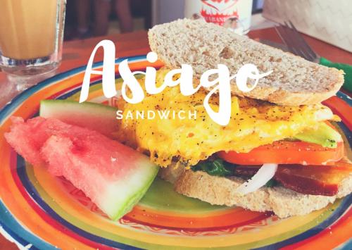 a plate with an egg sandwich and a slice of watermelon at Marbucks Bed & Breakfast in San Pedro