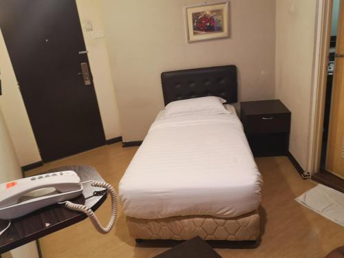 a small bed in a room with a phone at Sai Villa Hotel Near Klia & Klia2 in Nilai