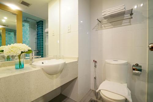 La salle de bains blanche est pourvue de toilettes et d'un lavabo. dans l'établissement Oceania Hotel, à Kota Kinabalu