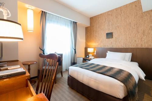 a hotel room with a large bed and a desk at Matsumoto Marunouchi Hotel in Matsumoto