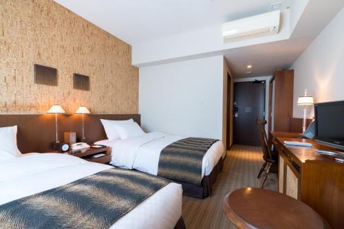 a hotel room with two beds and a desk and a television at Matsumoto Marunouchi Hotel in Matsumoto