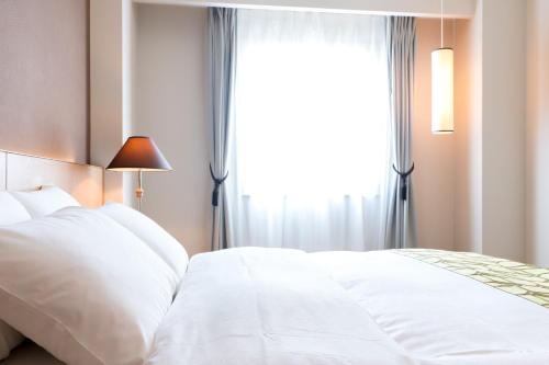 a bedroom with a white bed with a window at Matsumoto Marunouchi Hotel in Matsumoto