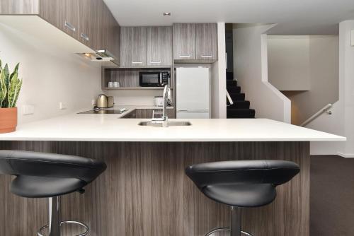 a kitchen with a white counter and black stools at Armagh Apartment 3 - Christchurch Holiday Homes in Christchurch