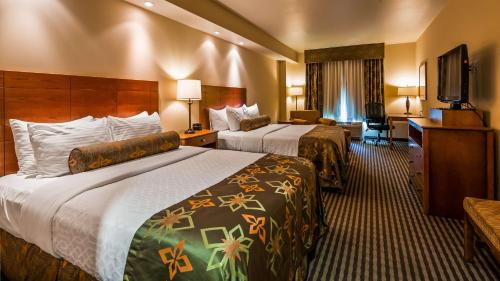 una camera d'albergo con due letti e una televisione di Best Western PLUS Westgate Inn and Suites a Leland