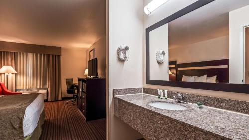 a hotel room with a bed and a bathroom with a sink at Best Western Parsons Inn in Parsons