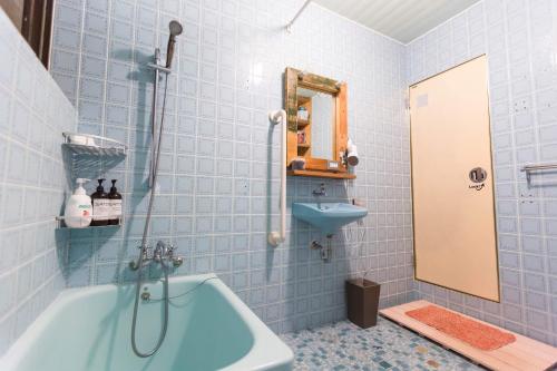 a blue tiled bathroom with a tub and a sink at hamaca117 in Motobu