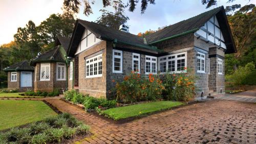 努沃勒埃利耶的住宿－Scottish Planter Bungalow- Thema Collection，前面有花园的砖房