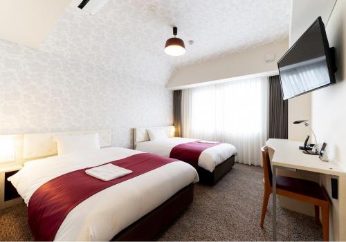 a hotel room with two beds and a desk at Hotel Rosso Karuizawa in Karuizawa