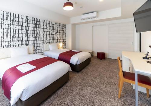 a hotel room with two beds and a desk at Hotel Rosso Karuizawa in Karuizawa