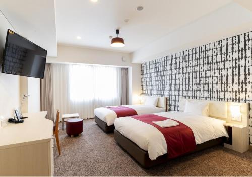 a hotel room with two beds and a flat screen tv at Hotel Rosso Karuizawa in Karuizawa