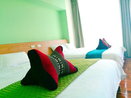 two beds with pillows on them in a bedroom at 198紅帽民宿l市區l2025冷氣全面換新 in Magong