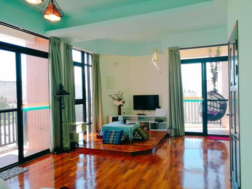 a living room with wooden floors and large windows at 198紅帽民宿l市區l2025冷氣全面換新 in Magong