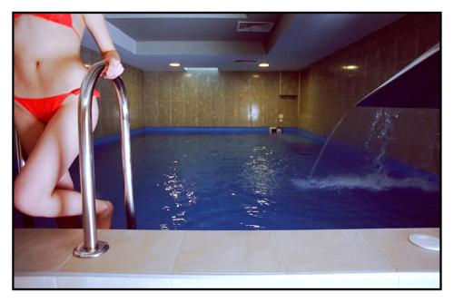 Eine Frau in einem roten Kleid steht im Pool in der Unterkunft Boutique Hotel Korana Srakovcic in Karlovac