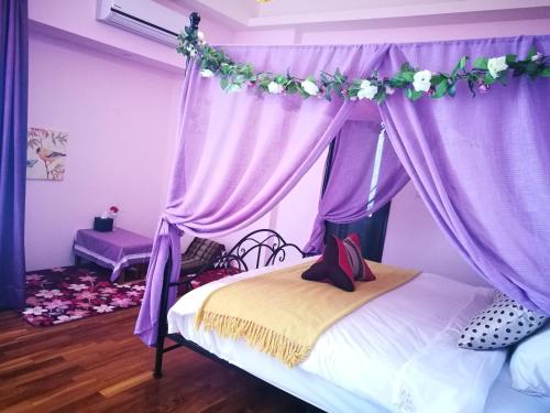 a bedroom with a canopy with purple curtains and flowers at 198紅帽民宿l市區l2025冷氣全面換新 in Magong