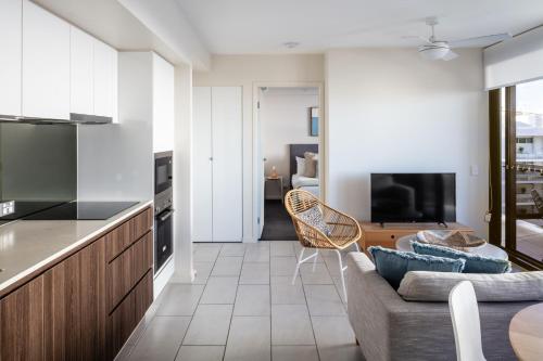 a kitchen and living room with a couch and a tv at First Light Mooloolaba, an Ascend Collection Hotel in Mooloolaba