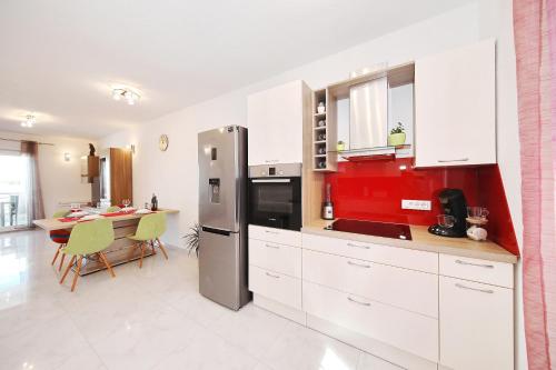 a kitchen with a refrigerator and a table with chairs at Apartment Lana in Pašman
