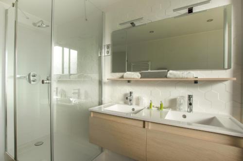 uma casa de banho com um lavatório e um chuveiro com um espelho. em Cit'Hotel Imperial em Sète