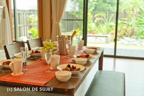a long wooden table with plates of food on it at Bougain Terrace Resort Thi-chi House in Nago