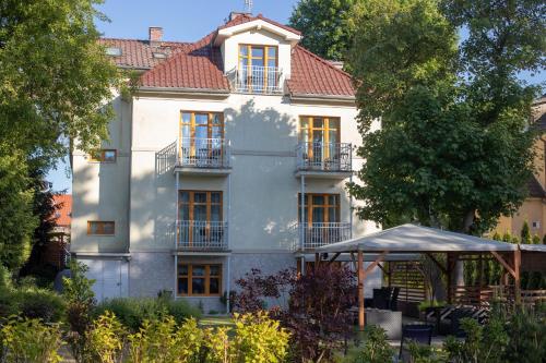 a large white house with windows and a roof at Willa Pod Lipami in Świnoujście