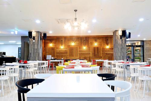 a dining room with white tables and chairs at Grandmillions Hotel Seogwipo in Seogwipo