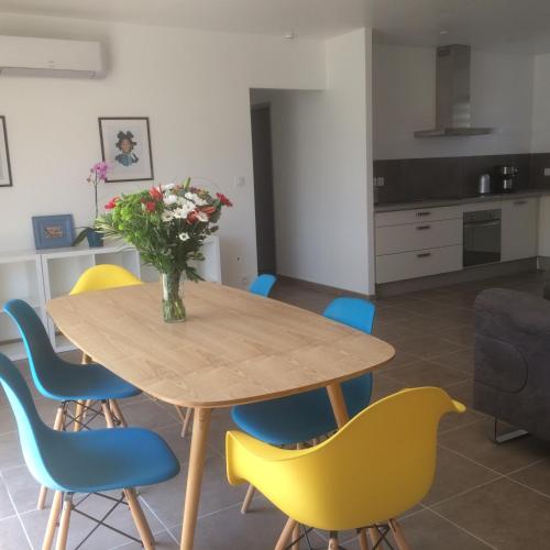une table à manger avec des chaises et un vase de fleurs dans l'établissement Lou Badabeu, à Le Barroux