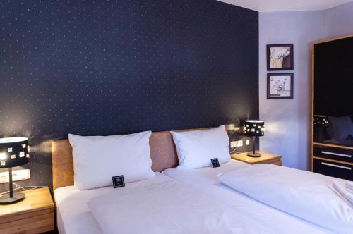 a bedroom with a bed with white sheets and two lamps at Arthotel ANA Aura in Aystetten