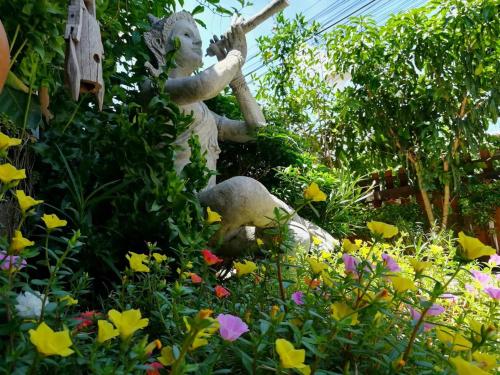 a statue in a garden with flowers at Lampang Lanna Home in Lampang