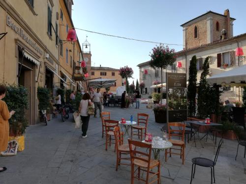 a street with tables and chairs and people walking down the street at MADI' casa vacanze in Laiatico